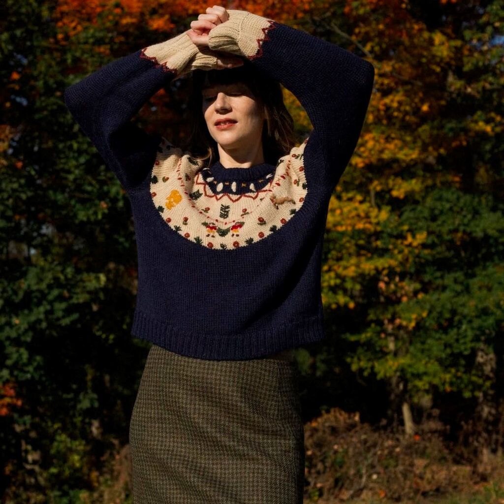 woman in a hand-embroidered navy blue winter sweater with wool tweed skirt