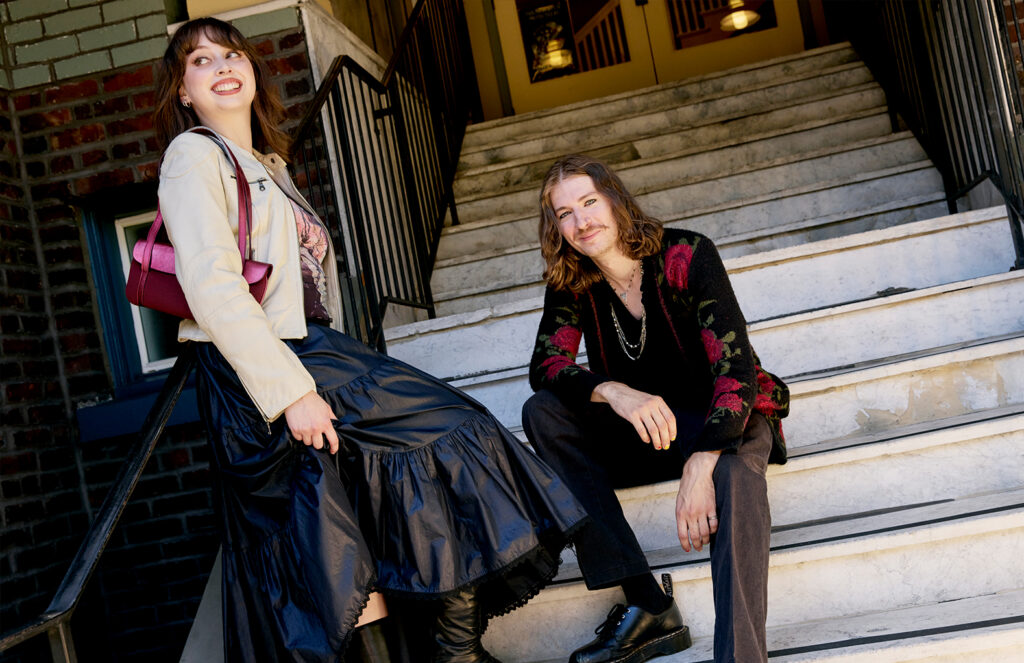 Claire and Aleks wearing winter fashion sitting on stairs