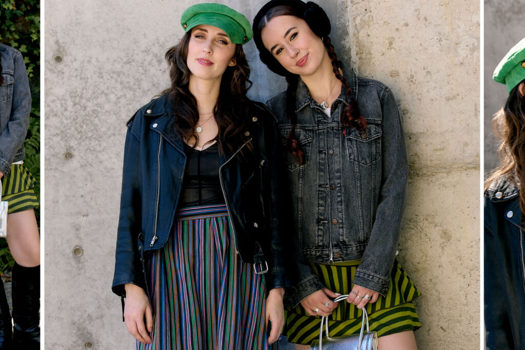 Marie and Meghan wearing winter fashion leaning against a grey concrete wall