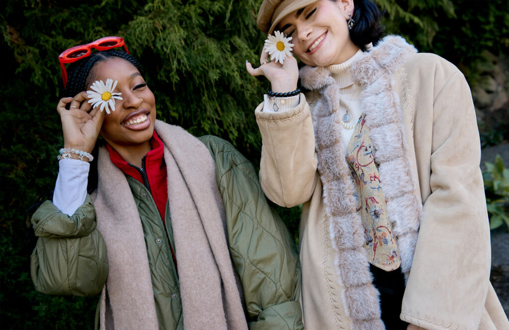 Tonoya and Renee holding a daisy in front of one eye and smiling