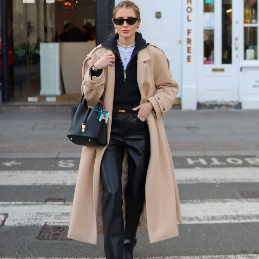 woman in black leather pants, a black sweater, and long tan trench coat