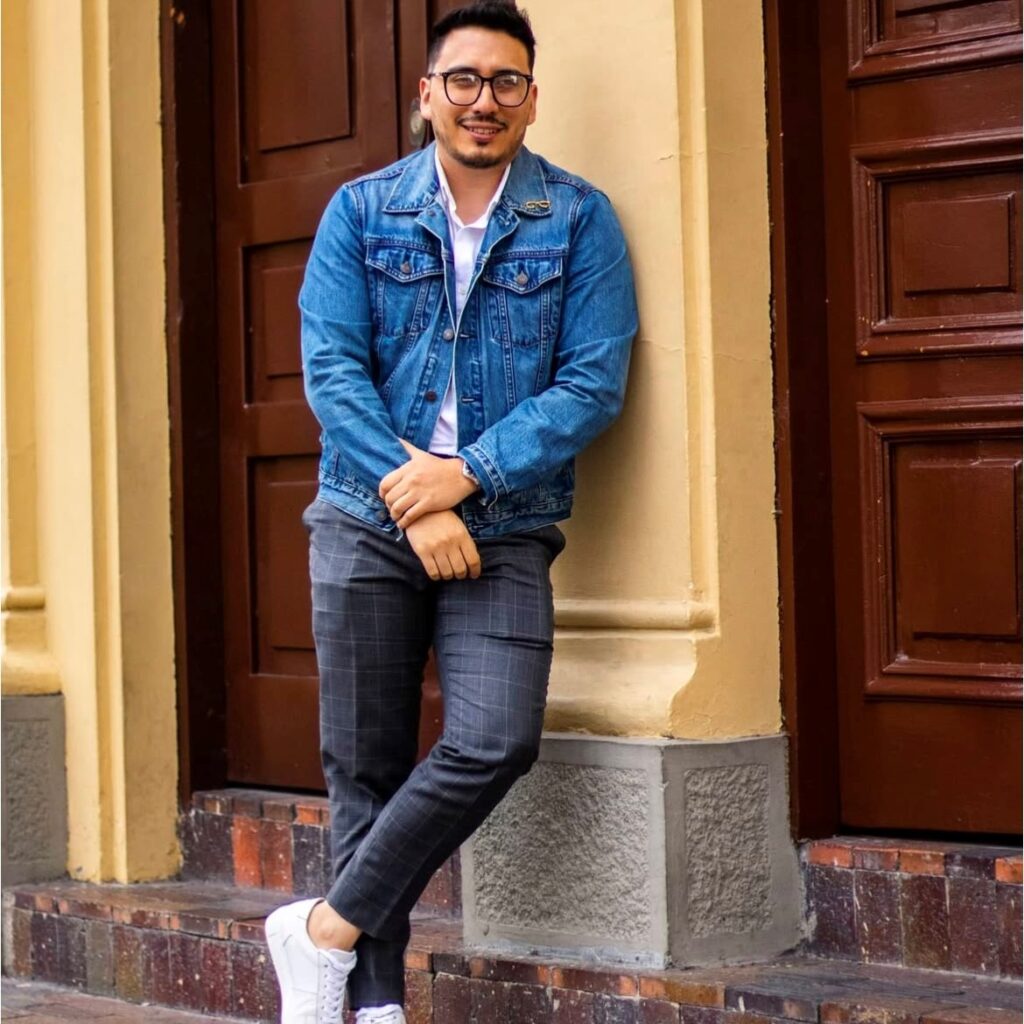 man wearing a denim jacket, polo shirt, and gray trousers