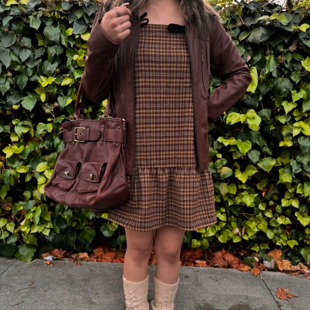 person holding a brown leather bag with gold hardware