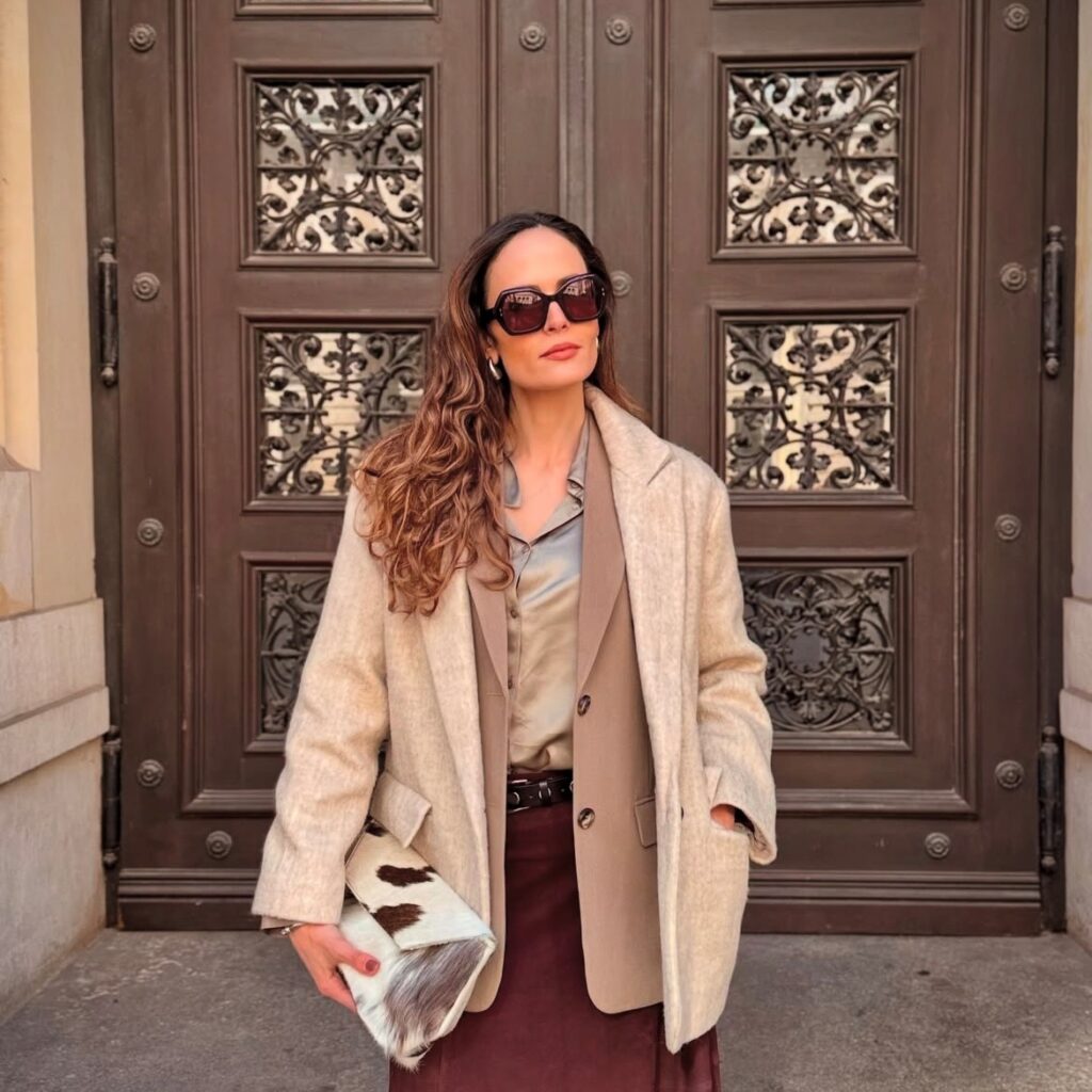 woman in maroon skirt, tan blouse, taupe blazer and sand-colored jacket