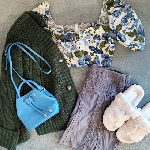 flatlay of green cardigan, floral top, and lavender shorts