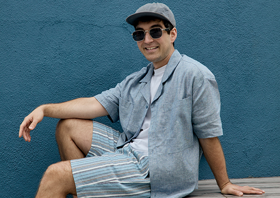 Charlie wearing a blue short sleeve button up over a white tee and striped shorts