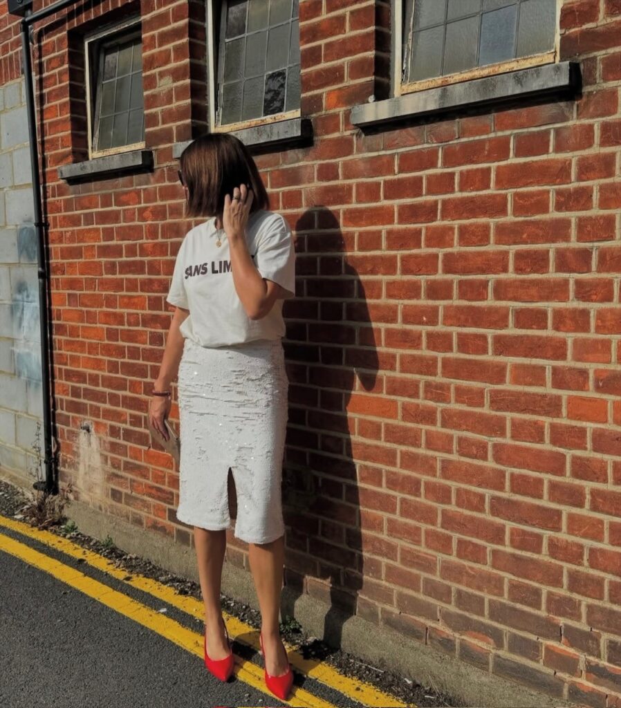 woman in white tee and white sequin skirt with red high heels