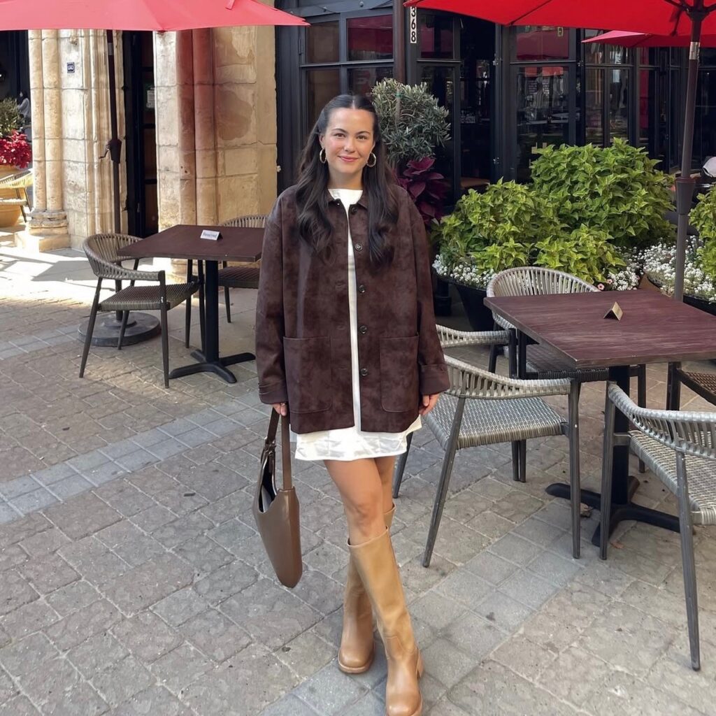 woman in brown suede jacket with cream-colored mini dress and tall tan boots