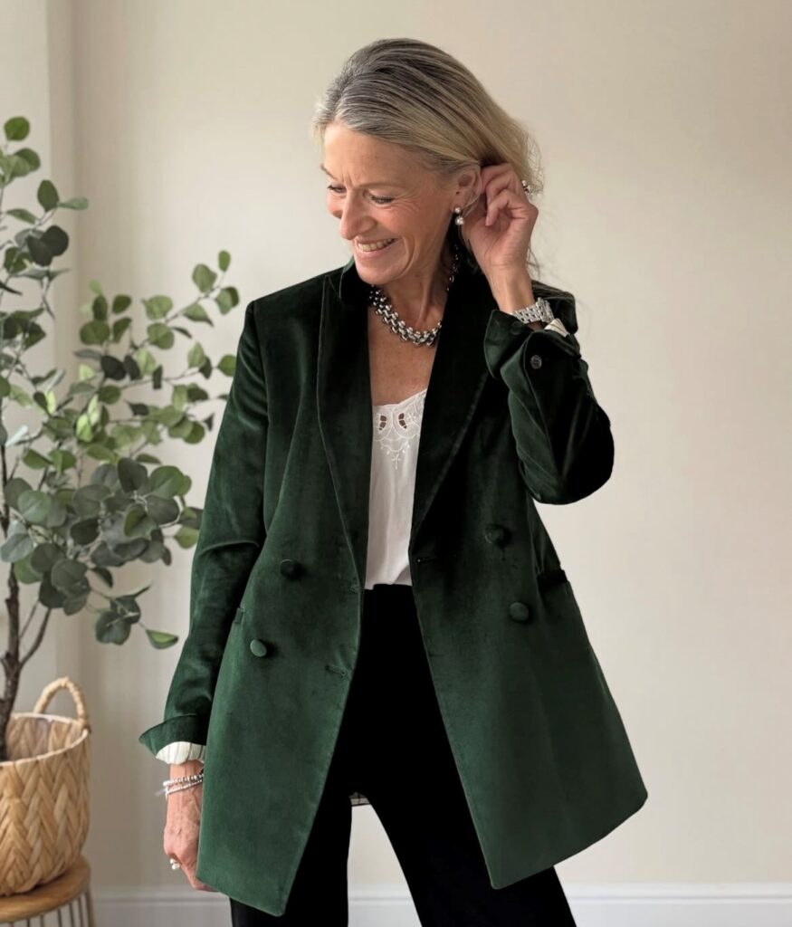 woman wearing a green velvet blazer with cream-colored camisole and black pants