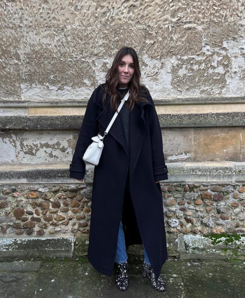 woman in long overcoat, jeans, and sequin booties