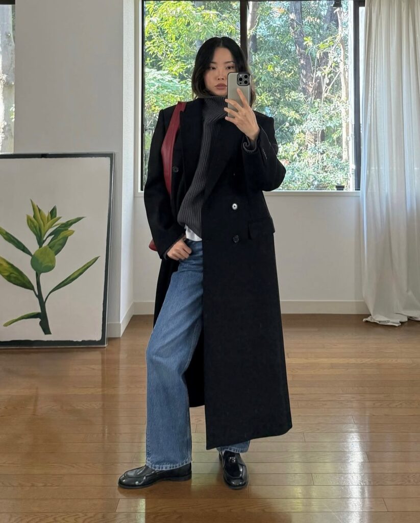 woman in coat, sweater, and jeans