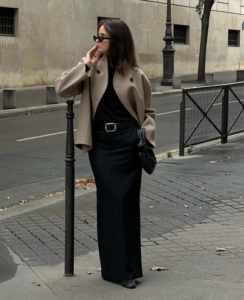 woman in long black skirt, black tee, and tan blazer