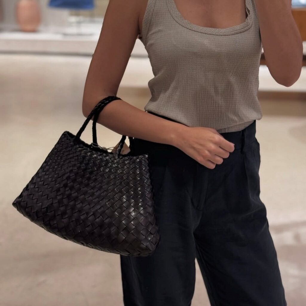 woman holding a black woven bag