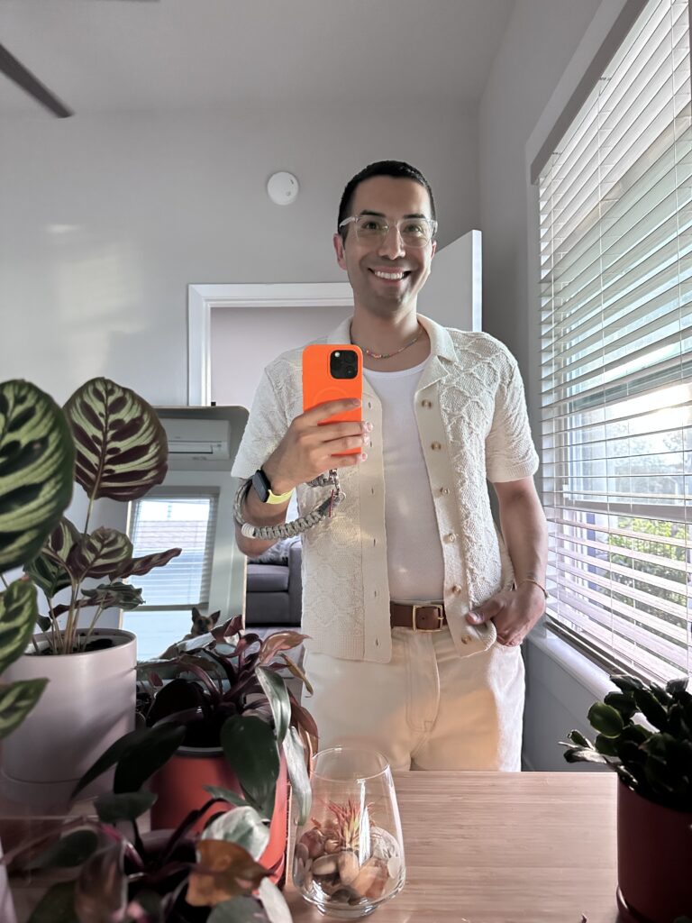 Jason in a white tank with a cream-colored knit and pants.