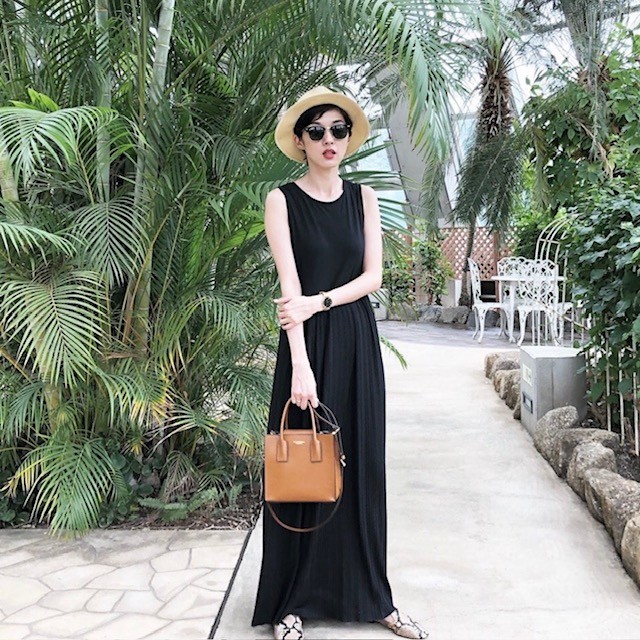 woman in black tank dress with straw hat and brown handbag