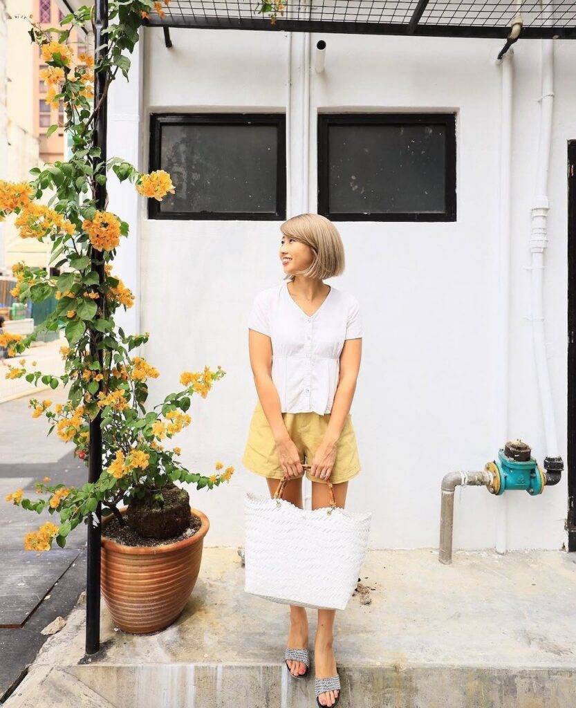 Woman holding a straw tote bag with bamboo handle