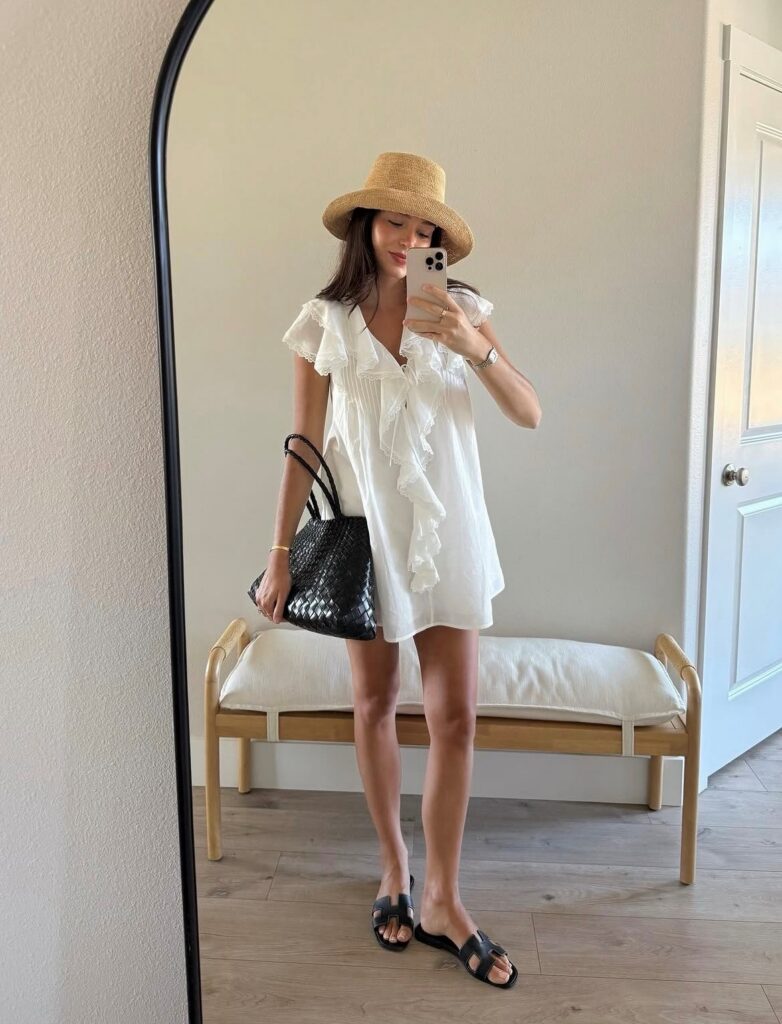 woman in white cotton dress with black sandals and straw hat