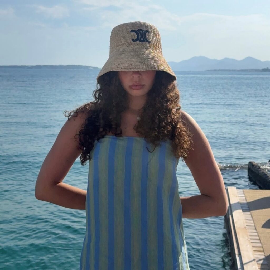 Woman wearing a bucket hat with striped beach cover-up.