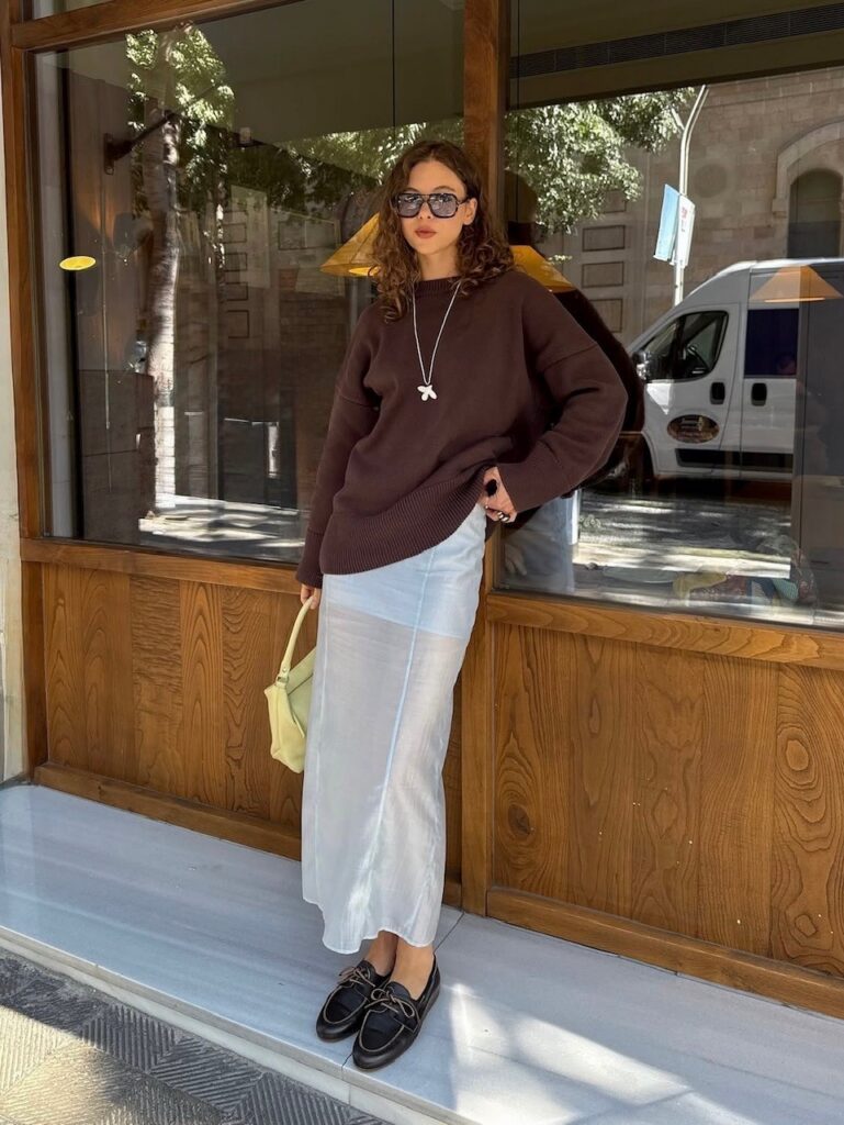 Woman in slip skirt and brown sweater with boat shoes