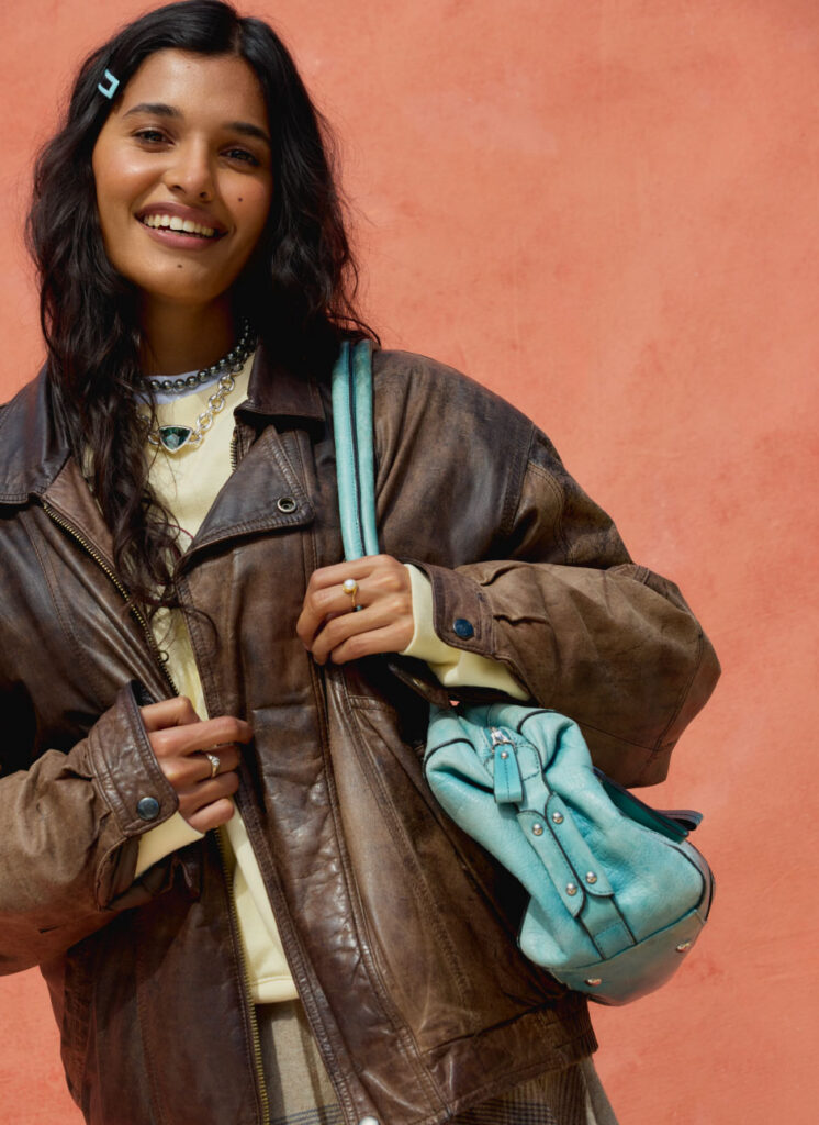 back to school clothes student in a pleated skirt, leather jacket, and sweatshirt, with turquoise bag