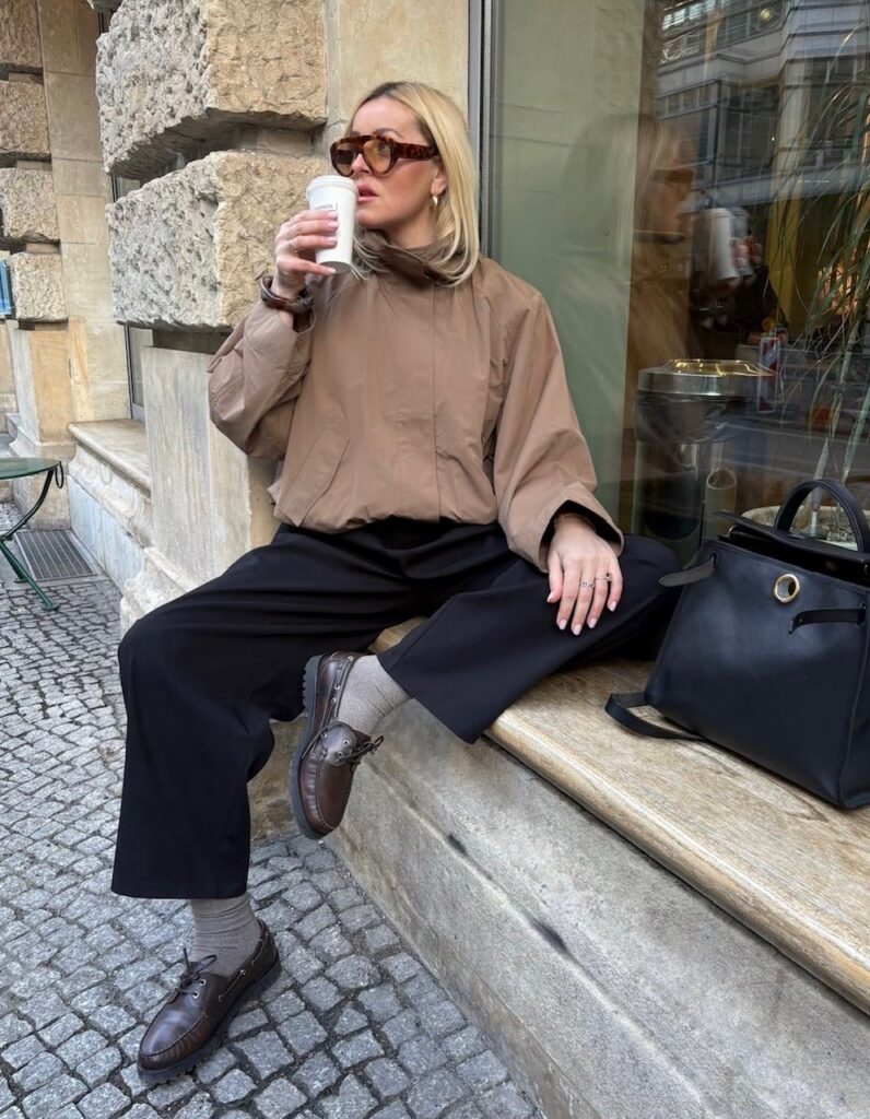 woman in tan funnel neck nylon jacket with black trousers