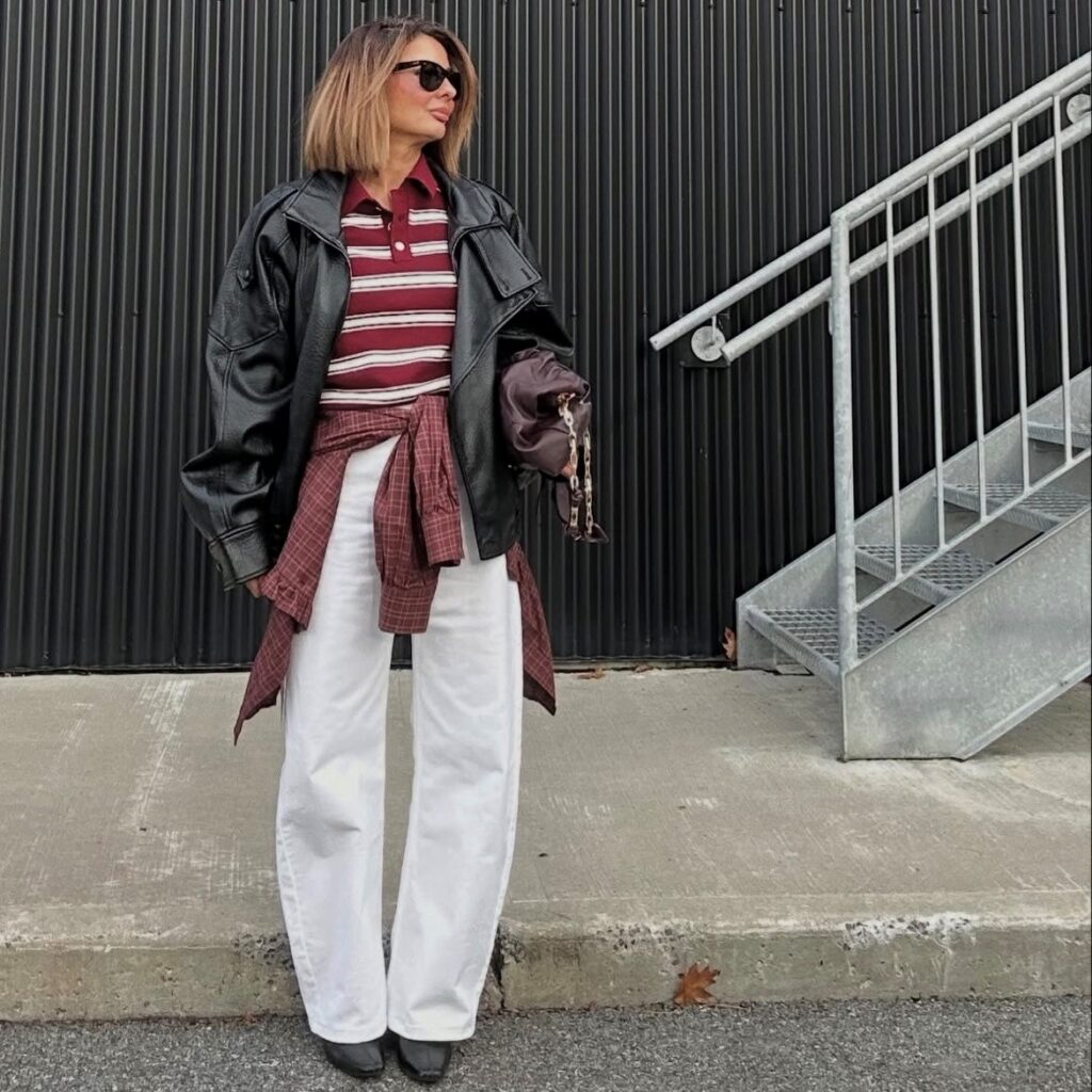 woman in white jeans, striped polo, and leather jacket