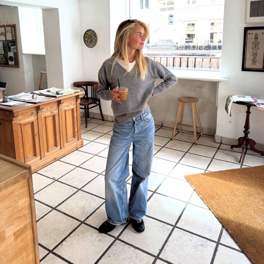woman in puddle jeans, white tee, and gray v-neck sweater